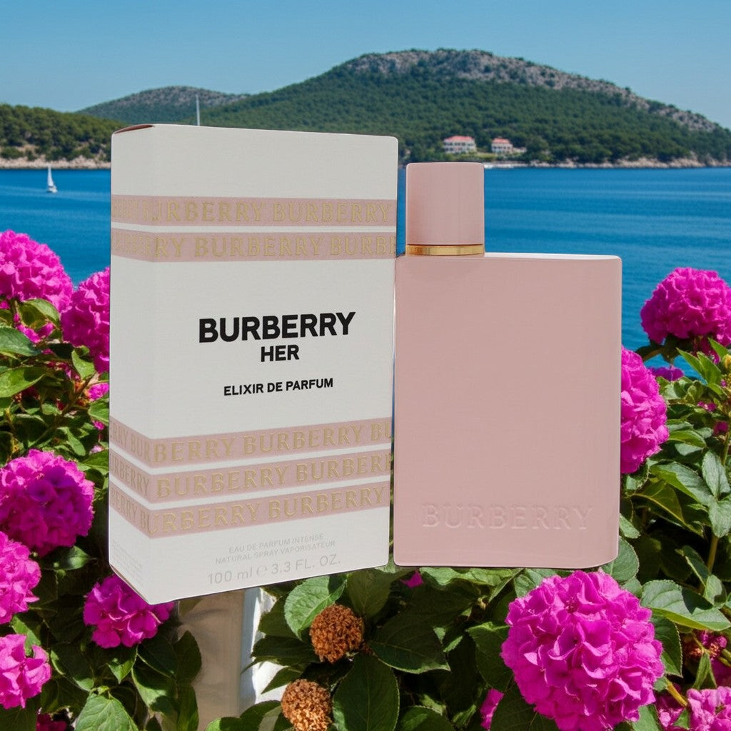 AuraGlow Burberry Her Elixir Eau de Parfum Intense bottle and box set surrounded by pink hydrangeas near the ocean.