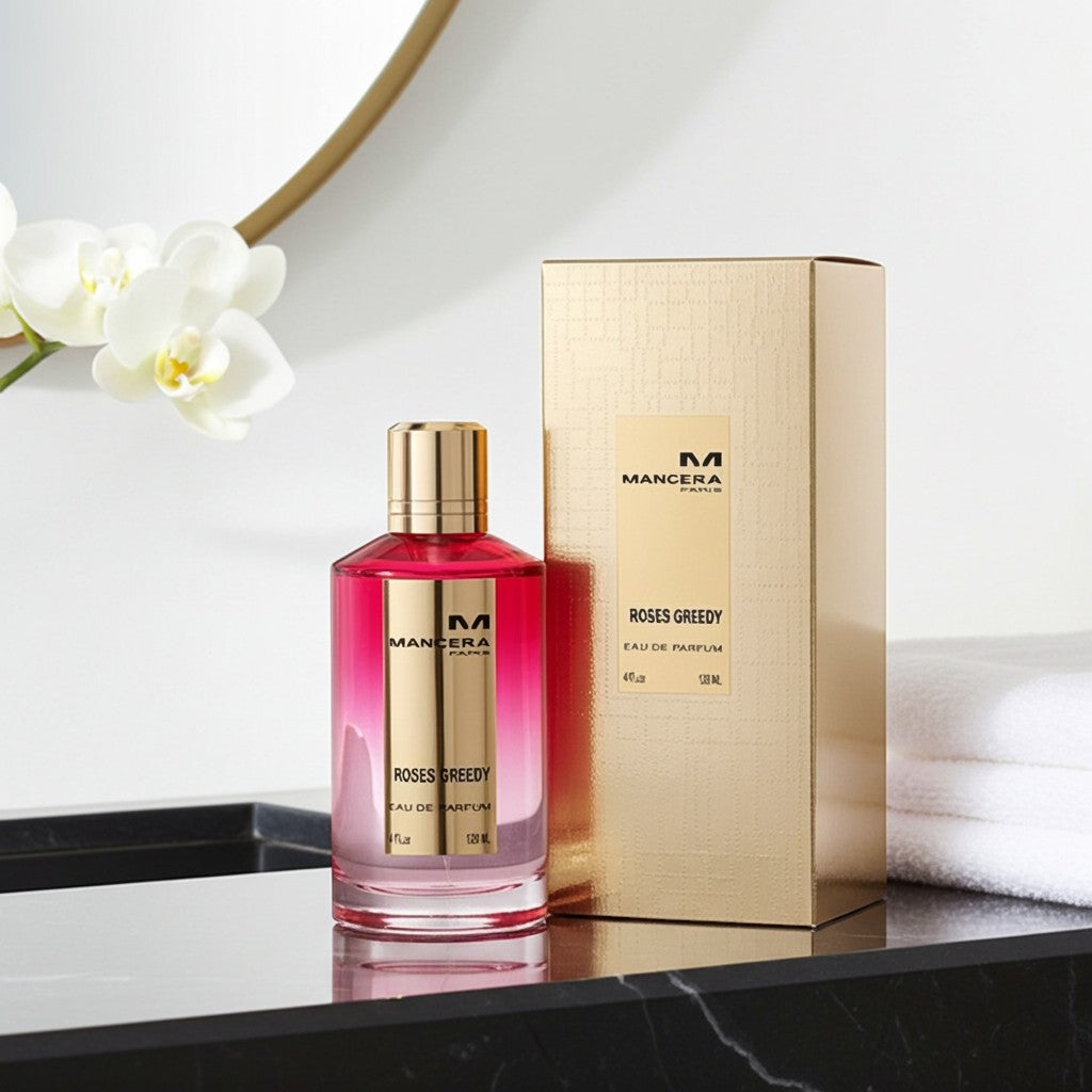 AuraGlow Mancera Roses Greedy unisex eau de parfum bottle and gold box on a marble vanity with white orchids.