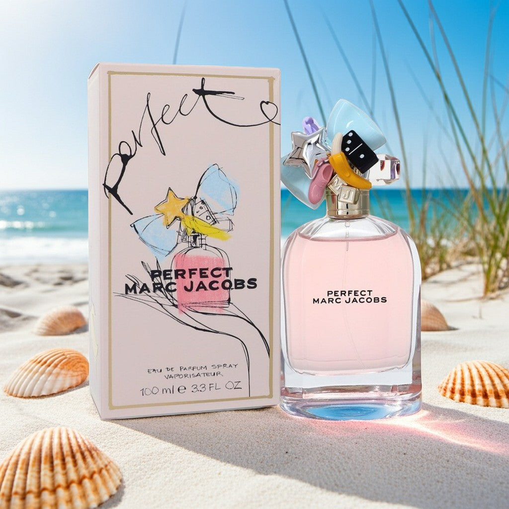 AuraGlow Marc Jacobs Perfect Eau De Parfum 3.3oz bottle and box on a sandy beach with seashells and ocean background.