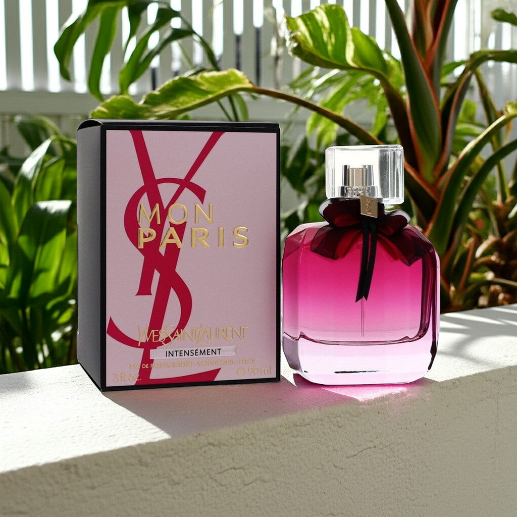 AuraGlow YSL Mon Paris Intensement perfume bottle and box with pink gradient glass and black bow in a garden setting